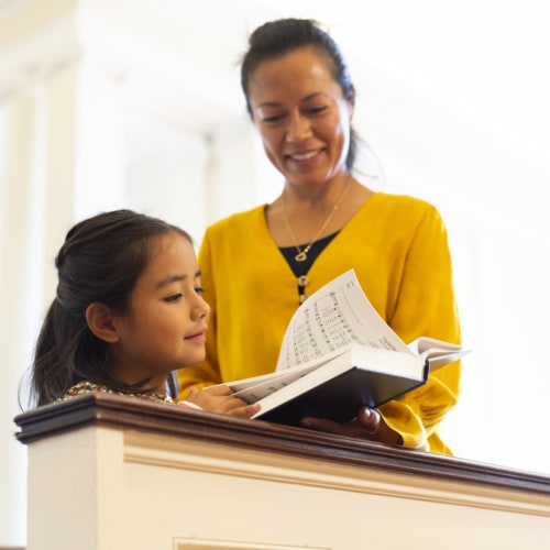 Mother and daughter hold hymnal