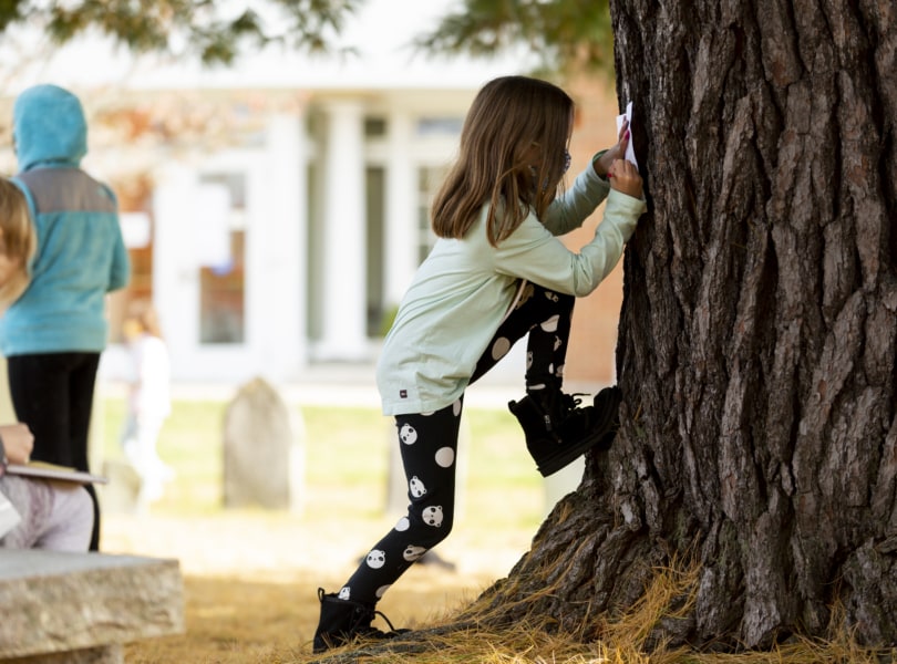 Child leans against tree