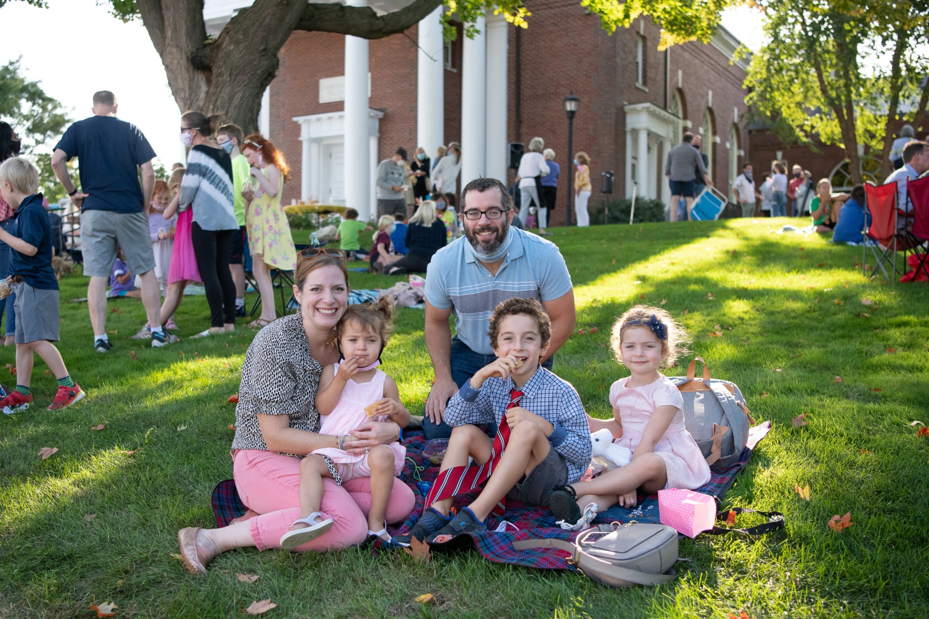 A familyi of five sits on the green in front of the Wellesley Village Church