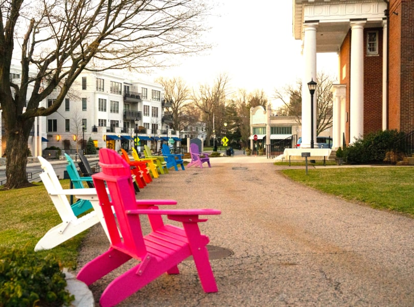 Rainbow-colored Adirondack chairs in cloister garden